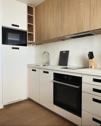 a kitchen with white cabinets and a black stove top oven at BÈTH CÈU - 4 PERS - Appart vacances- in Arette