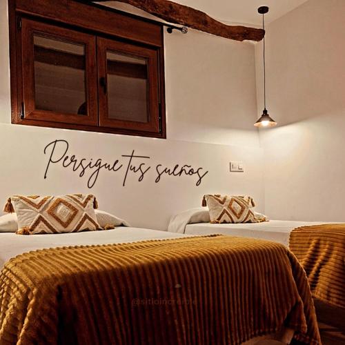 a bedroom with two beds with a sign on the wall at El Mirador de Teo in Alocén