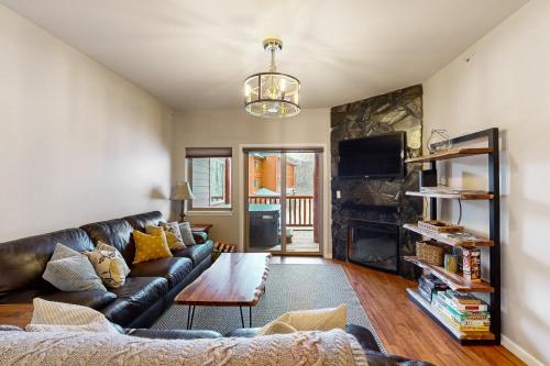 a living room with a leather couch and a fireplace at Hightower Hideaway in Girdwood