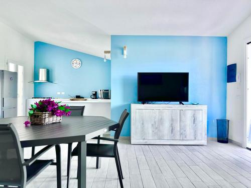 a dining room with a table and a tv on a blue wall at Villa Neni - Key to Villas in Valledoria