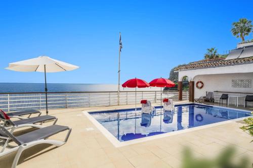 a swimming pool with chairs and umbrellas and the ocean at Villa Sea Shore by Villa Plus in Gaula