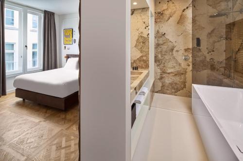 a bedroom with a bed and a shower and a tub at Boutique Hotel DARQ in Maastricht