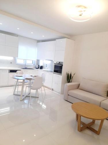 a white living room with a couch and a table at White Dome Apartment I in Souda