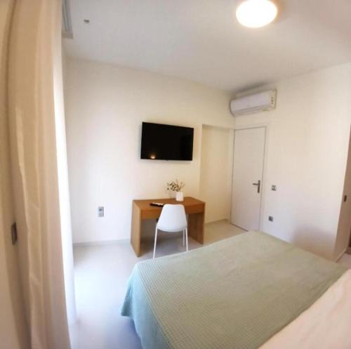 a bedroom with a bed and a desk and a tv at White Dome Apartment I in Souda
