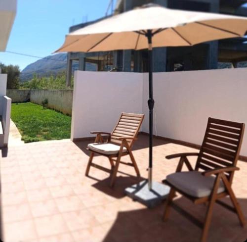 two chairs and an umbrella on a patio at White Dome Apartment I in Souda