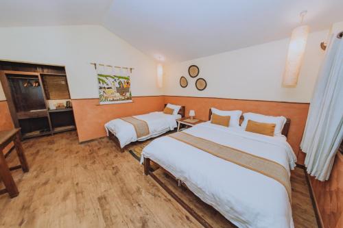 a hotel room with two beds and a desk at Machan Country Villa in Chitwan