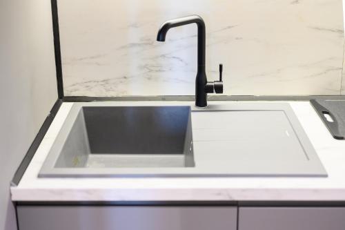 a white kitchen sink with a black faucet at Adore Home in Tirana