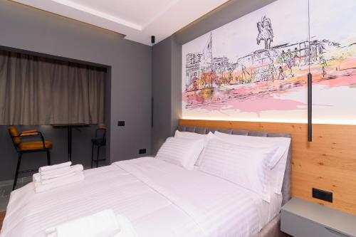 a bedroom with a white bed with a painting on the wall at Adore Home in Tirana