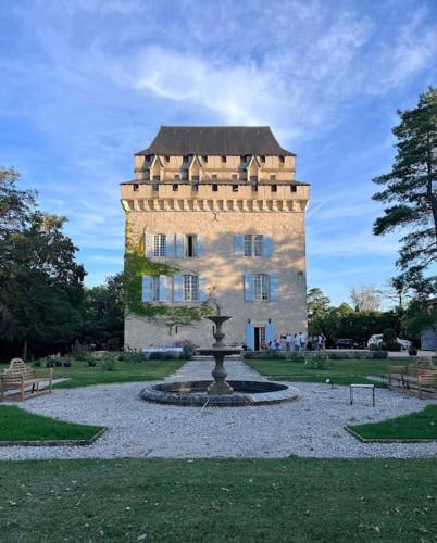 un bâtiment avec une fontaine devant un bâtiment dans l'établissement Château Tour du XIII siècle Gazaupouy, à Gazaupouy