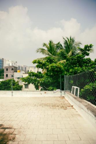 a tennis court with a fence and palm trees at Hostel Gandhi in Chennai