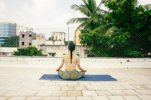 a woman sitting on the ground in a yoga pose at Hostel Gandhi in Chennai