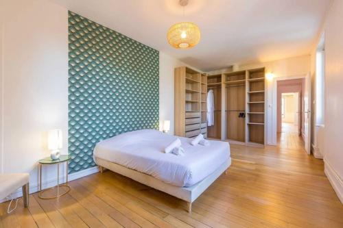 une chambre avec un lit blanc et un mur vert dans l'établissement Le Devosge, à Dijon