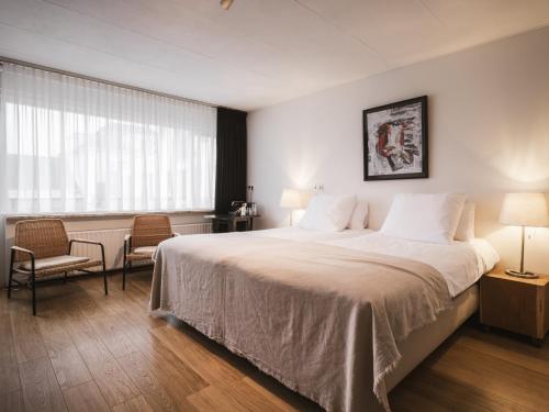 a hotel room with a large bed and a window at Strandhotel Domburg in Domburg