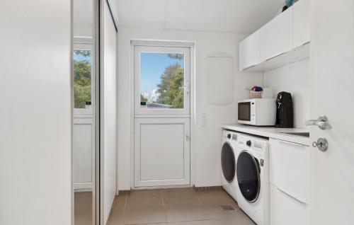 a white kitchen with a washing machine and a microwave at 3 Bedroom Cozy Home In Liseleje in Liseleje