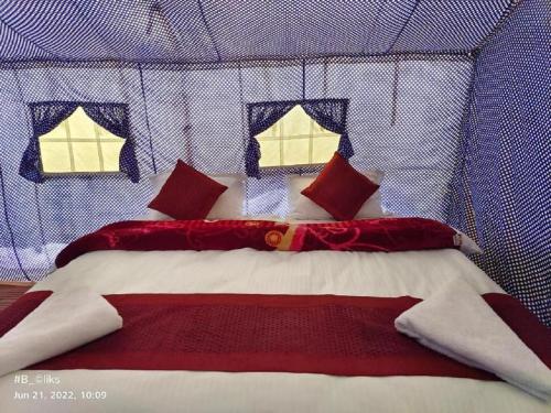 a bed with red and white sheets and pillows at Blue Waves Camps Lake View Pangong in Tangtse