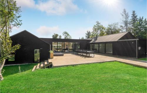 a black house with a deck and grass at Amazing Home In Fårevejle With Sauna in Fårevejle