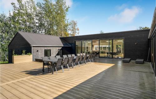 a black house with a deck with a table and chairs at Amazing Home In Fårevejle With Sauna in Fårevejle