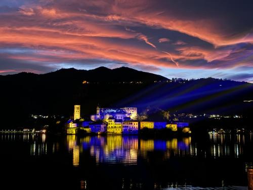 a lit up building on the water at night at -Ortaflats- Appartamento l'Isola in Orta San Giulio