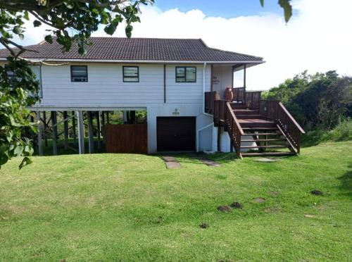 a white house with a large yard with a porch at Jolly Mooi's Beach Break in Gxara