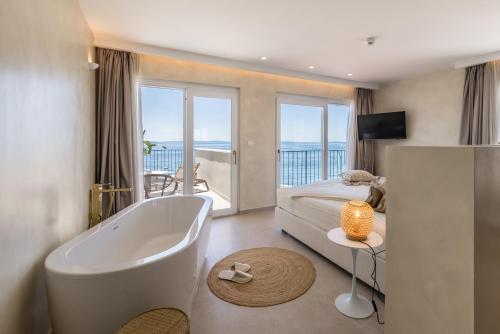 a bedroom with a tub and a bed and a balcony at Hotel Aria in Podstrana
