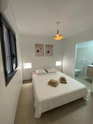une chambre blanche avec un lit avec deux serviettes dessus dans l'établissement Rez de villa Favone, à Conca