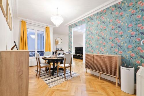 une salle à manger avec une table et un mur orné de fleurs dans l'établissement Charmant Appartement Arc de Triomphe Free Netflix, à Paris