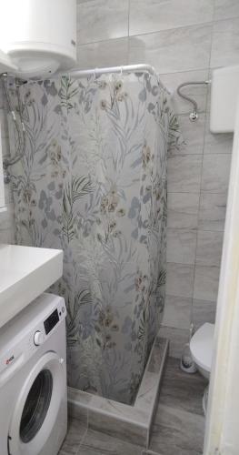 a bathroom with a toilet and a washing machine at Una Studio Apartman in Sombor