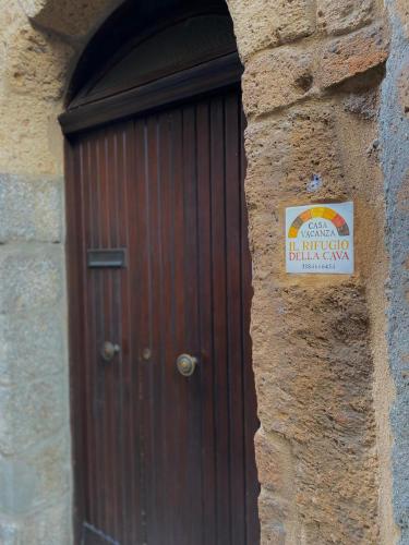 a wooden door in a stone building with a sign on it at il rifugio della cava in Orvieto