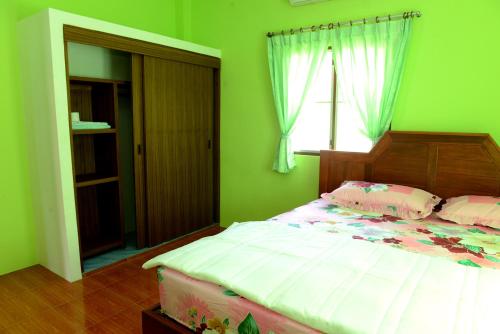 a bedroom with a bed with green walls and a window at New Sunrise Village in Mae Nam
