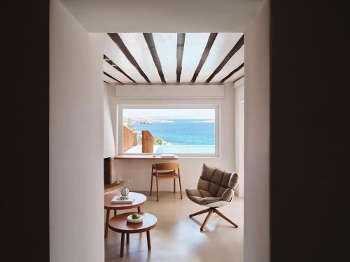 a room with a window and a chair and a table at Bill&Coo Mykonos-The Leading Hotels of the World in Mýkonos City