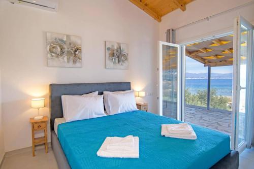 a bedroom with a blue bed with a view of the ocean at Villa Katostrato Beach by Villa Plus in Apraos