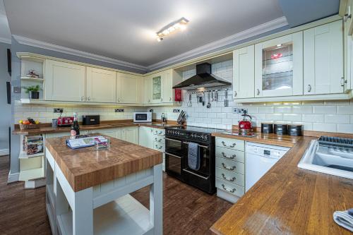 a kitchen with white cabinets and a wooden counter top at Snowdonia View in Llanfairpwllgwyngyll