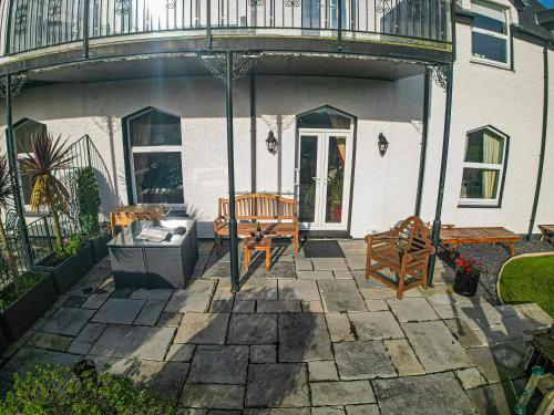 a patio with two benches and an umbrella at Snowdonia View in Llanfairpwllgwyngyll