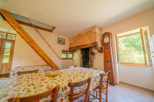 une salle à manger avec une table et une horloge dans l'établissement Maison de campagne à 5 kms de St Cirq Lapopie, à Cénevières