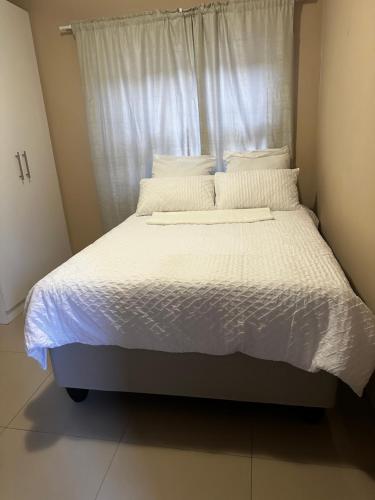 a bed with white sheets and pillows in a bedroom at Yamwaale Overnight Accommodation - Otjomuise Ext 4 in Windhoek