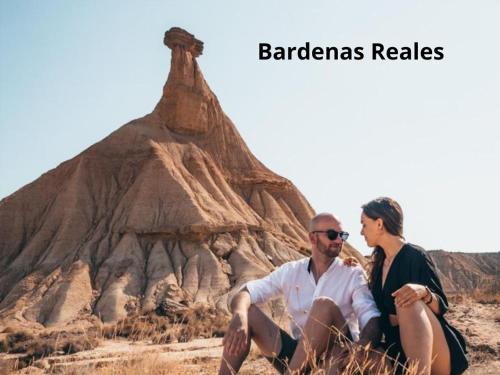 a man and a woman sitting in front of a desert mound at Hotel Rooms Ducay in Olite
