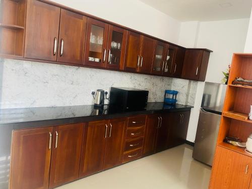 a kitchen with wooden cabinets and a refrigerator at Blue Star Apartments three bedroom apartment in Dehiwala