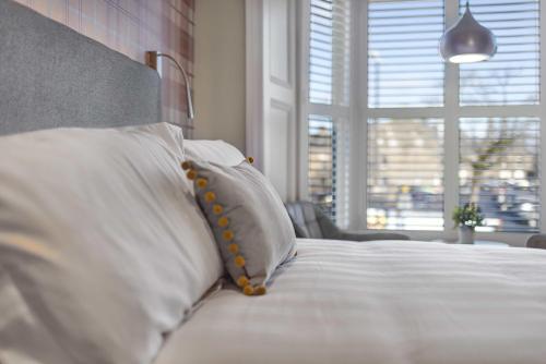 a bedroom with a bed with white pillows and a window at Rooms at The Vault in Buxton