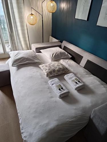 - un grand lit blanc avec 2 serviettes dans l'établissement Appartement Megara, à Montévrain