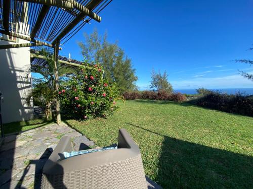 a wicker chair sitting under a pergola on a lawn at COCO MANGO Villa in Trèfles