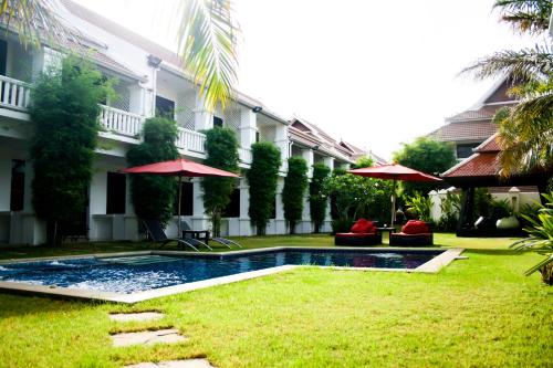 a swimming pool in front of a building with umbrellas at Palm Grove Resort, Pattaya in Na Jomtien
