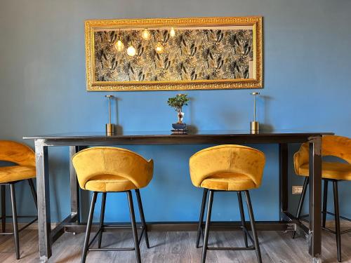 a table with yellow chairs and a picture on the wall at AlCivico3 in Civitanova Marche