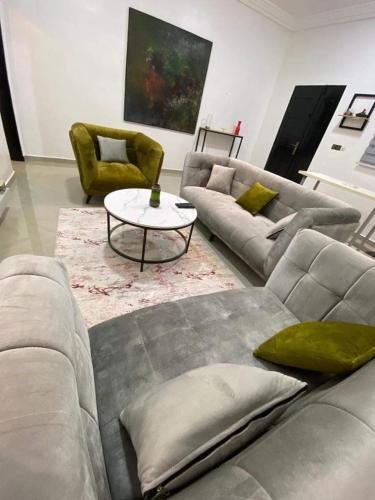 a living room with a couch and a table and chairs at Résidence ILEWA proche mer avec Terrasse Fidjrosse Cotonou in Cotonou