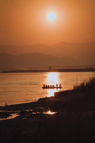 a group of rowers in the water at sunset at Machan Country Villa in Chitwan