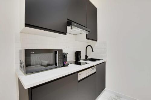 une cuisine avec un micro-ondes et un évier dans l'établissement Cosy modern flat - 1BR- 4P- Oberkampf, à Paris