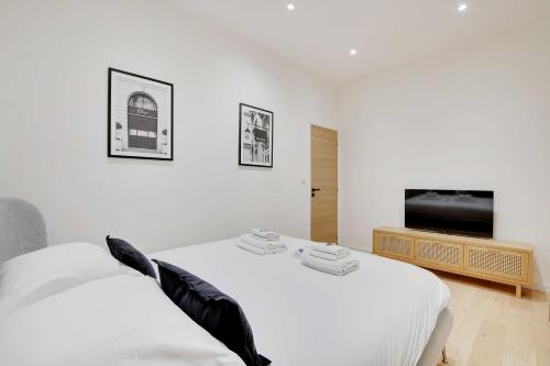 une chambre blanche avec un lit et une télévision à écran plat dans l'établissement Cosy modern flat - 1BR- 4P- Oberkampf, à Paris