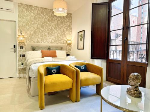 een slaapkamer met een bed en 2 gele stoelen bij Tennessee Petit Málaga in Málaga