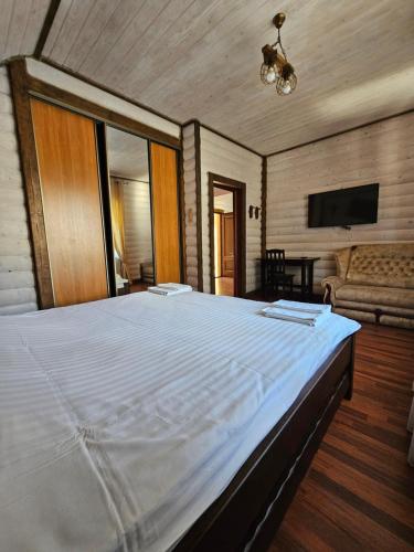 a large white bed in a room with a couch at L - Hutir in Mykulychyn