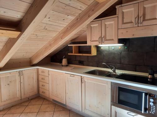 an attic kitchen with wooden cabinets and a sink at Chalet La Rugiada in Bormio