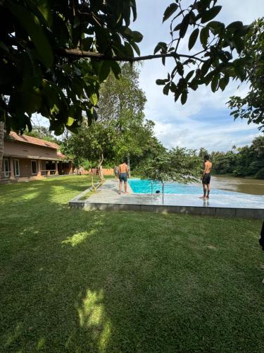 a group of people standing around a swimming pool at Theeram Riverside Holiday Home in Māla